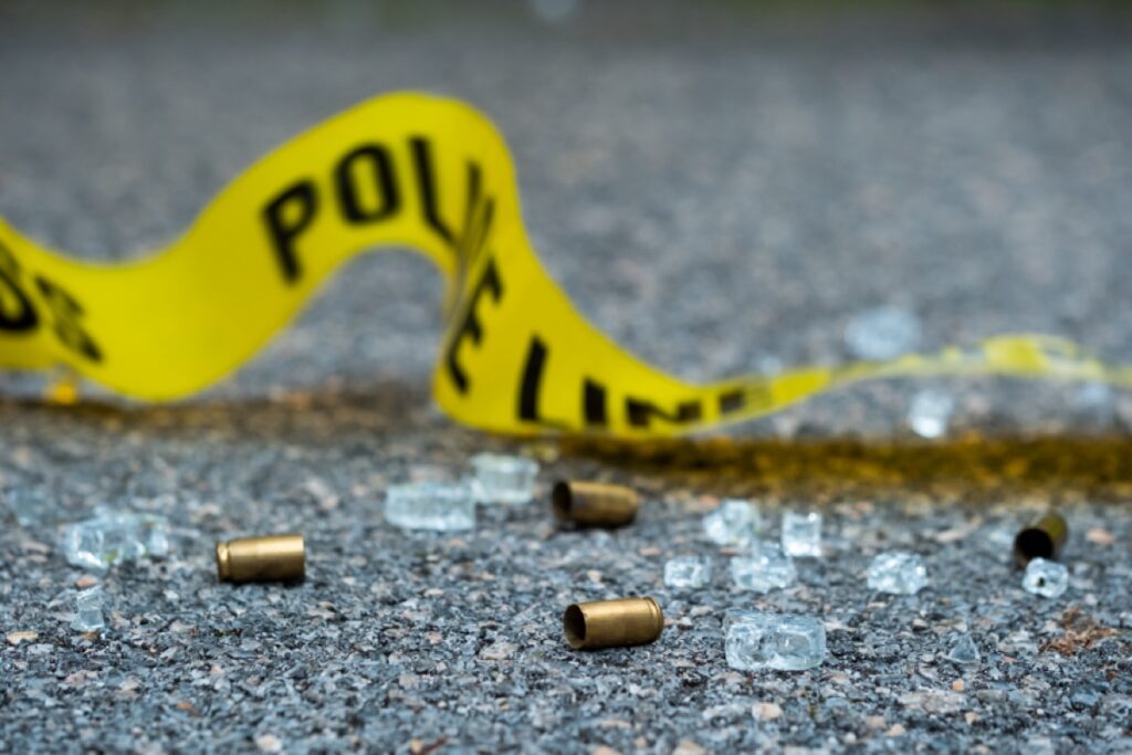 A bullet casing and police tape on the ground.