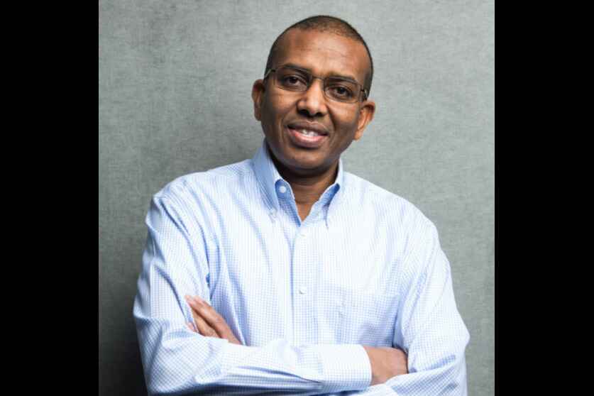 A man with his arms crossed wearing a blue shirt.