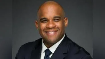 A man in a suit and tie smiling for the camera.