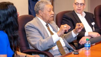 A man in suit and tie sitting at a table.