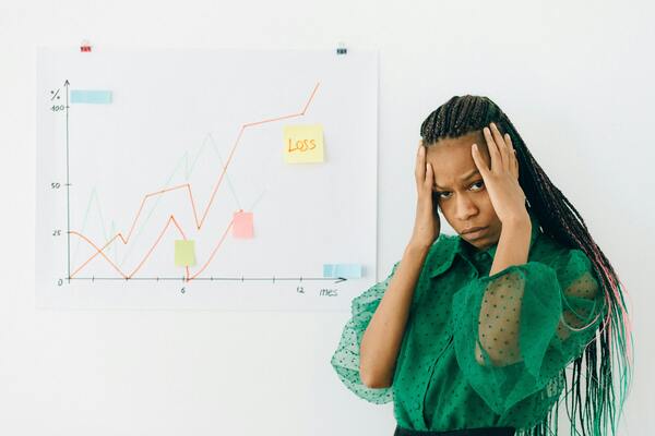 A woman holding her head in front of a whiteboard.