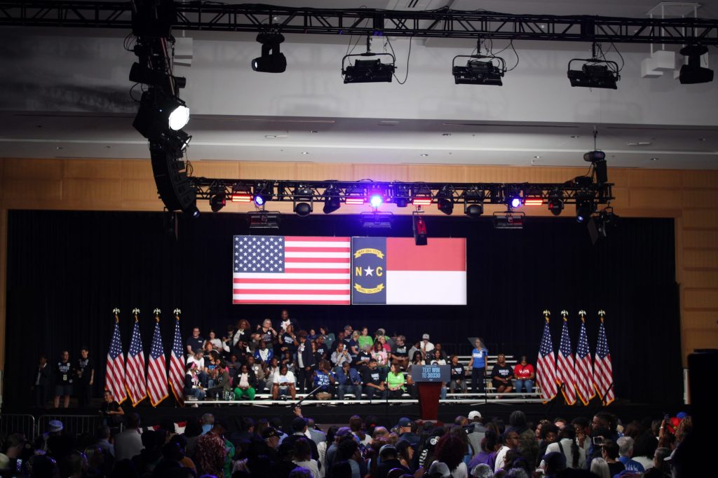 A crowd of people in front of two flags.