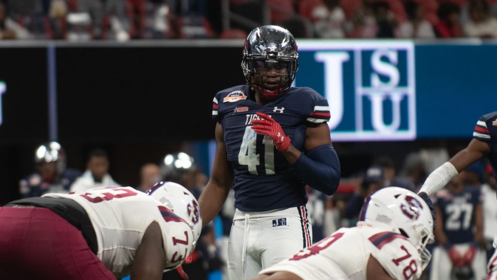 A football player is standing in the middle of a huddle.