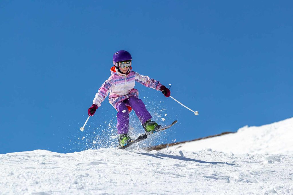 A young girl skiing down the side of a mountain.