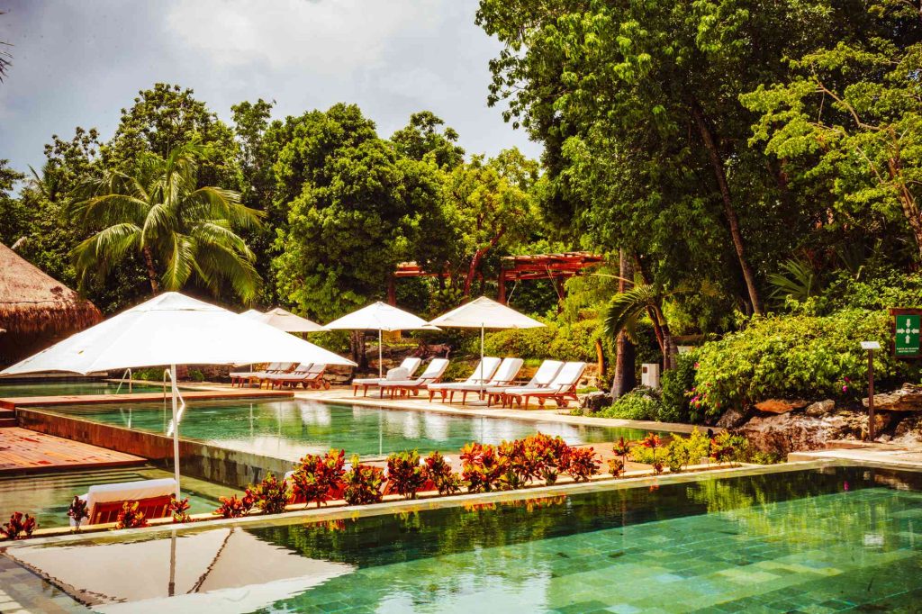 A pool with many chairs and umbrellas in the background.