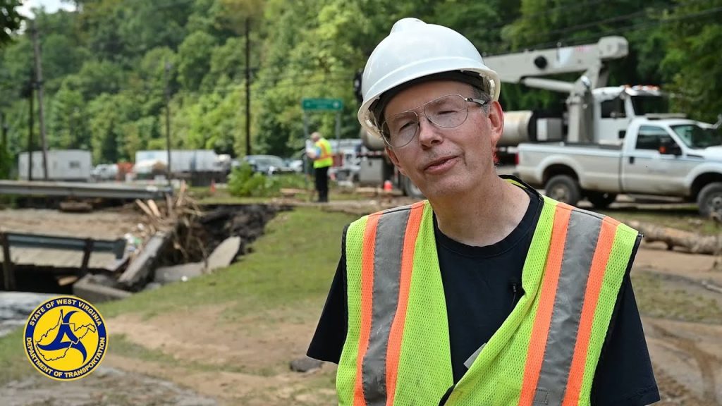 A man in safety gear standing next to a road.