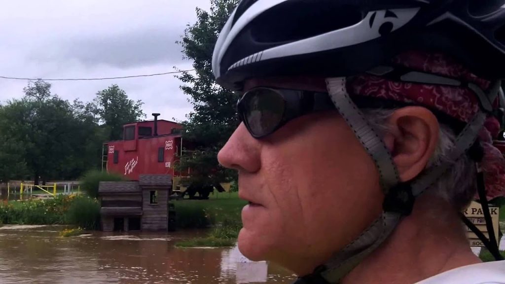 A man wearing a helmet and glasses near water.