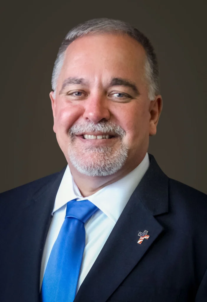 A man in a suit and tie smiling for the camera.