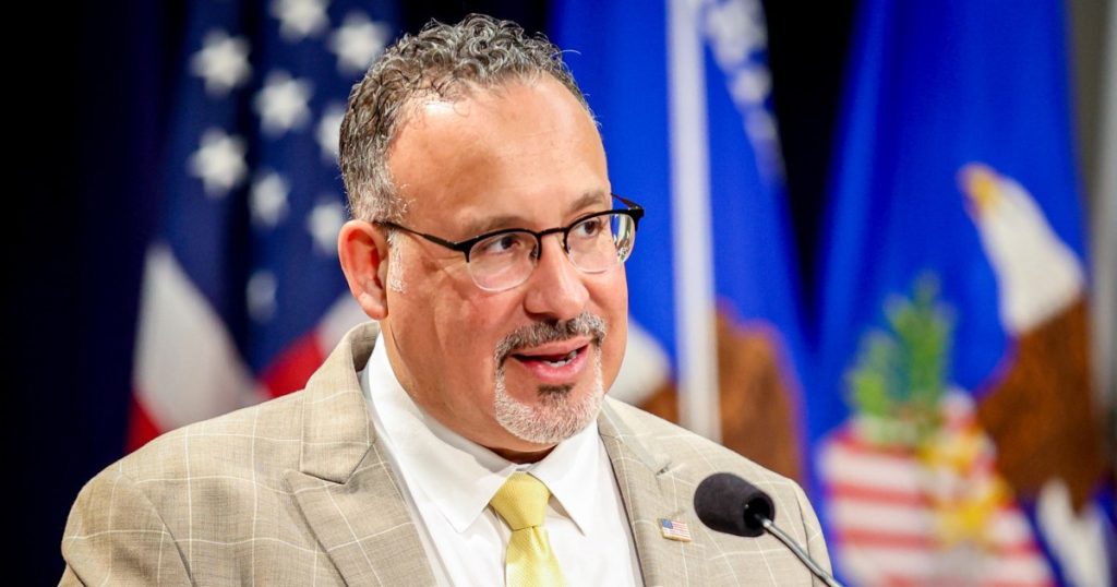 A man in glasses and suit is speaking at a podium.