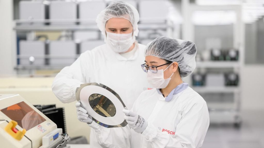 Two people in white lab coats and hats holding a plate.