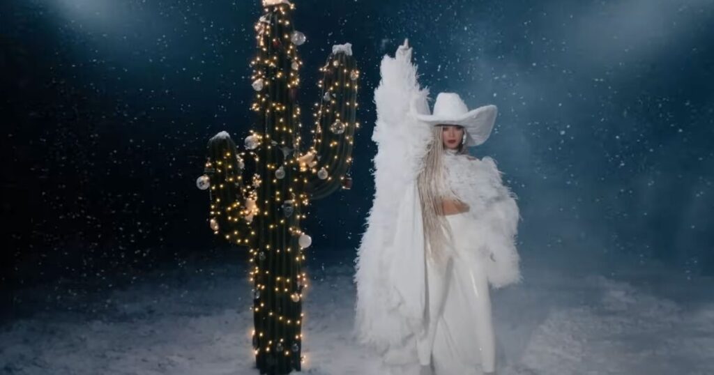 A person in white costume standing next to a cactus.