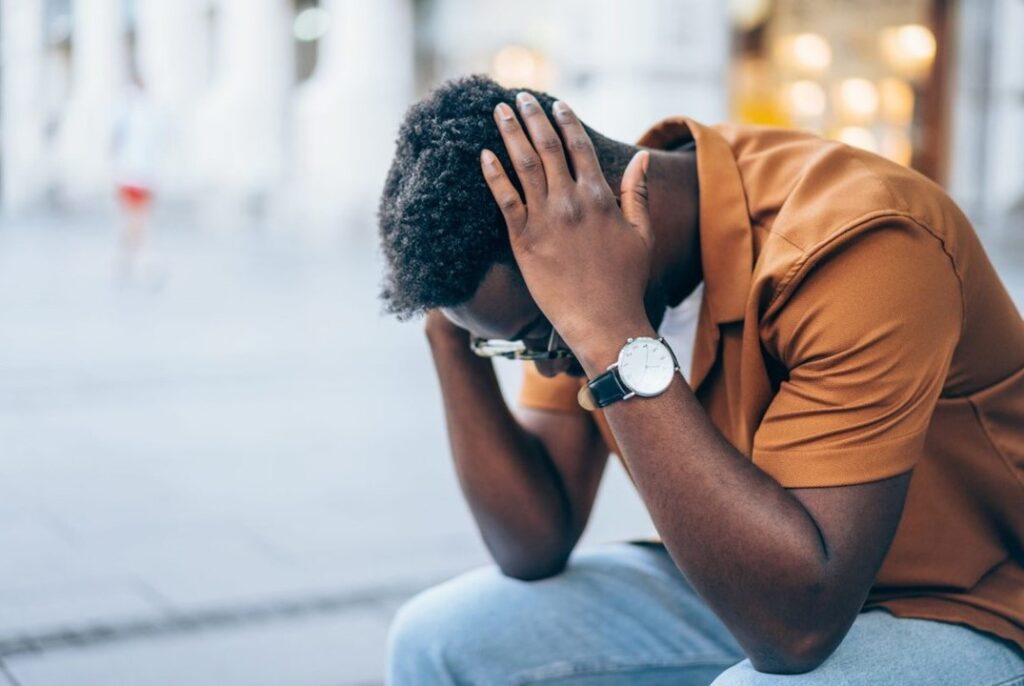 A man sitting down with his hands in his head.