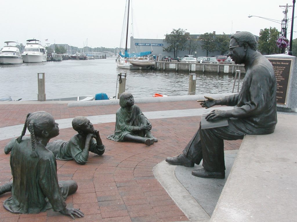 A statue of people sitting on the ground near water.