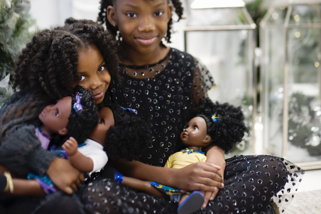 Two girls holding dolls and posing for a picture.