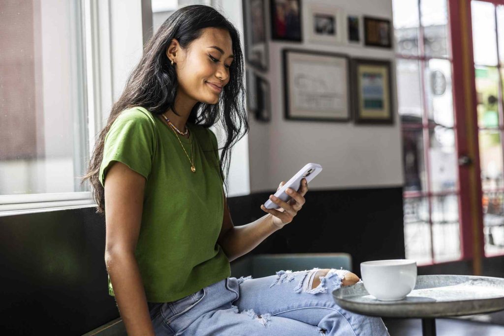 A woman sitting on the ground holding her phone.