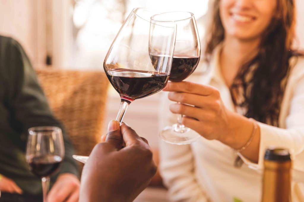 Two people holding wine glasses in a room.