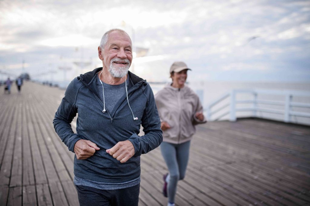 A man and woman running on the boardwalk.