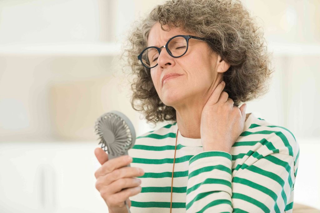 A woman with glasses holding a hair brush.