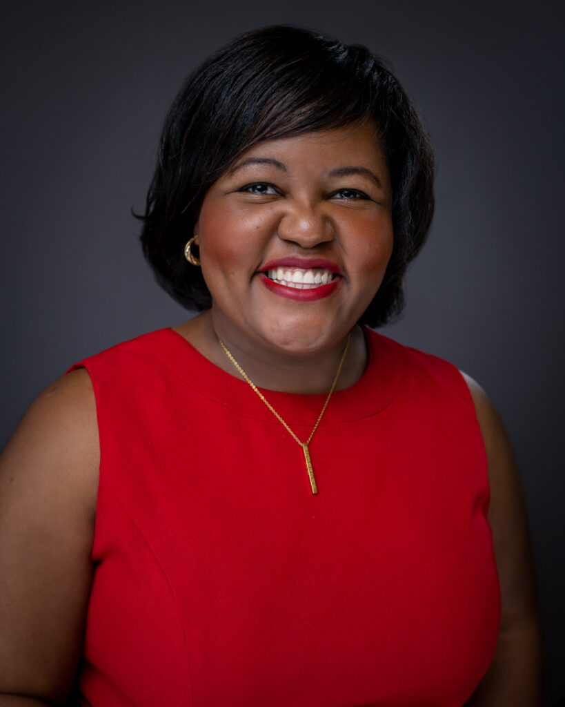 A woman in red shirt smiling for the camera.