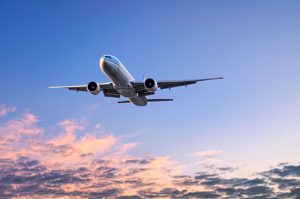 A large airplane flying in the sky at sunset.