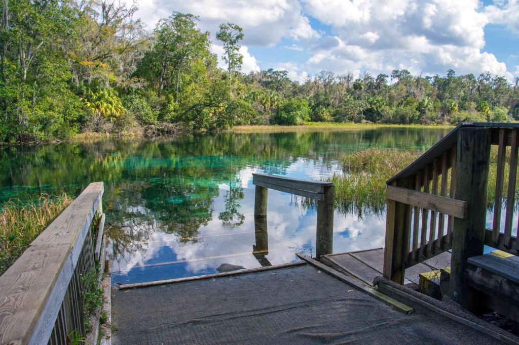 A dock with a wooden railing and water