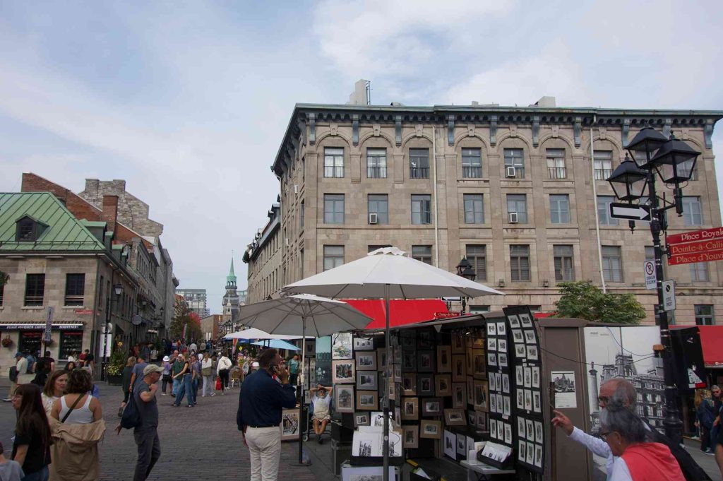 A street vendor selling pictures and umbrellas on the side of the road.