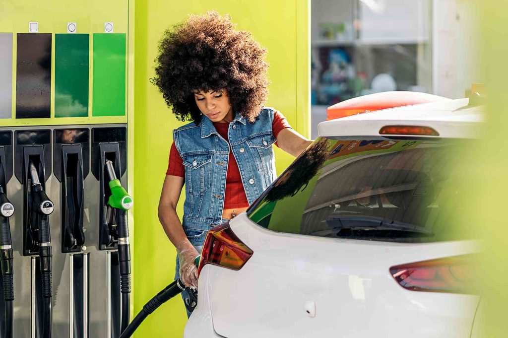 A woman pumping gas into her car at the station.