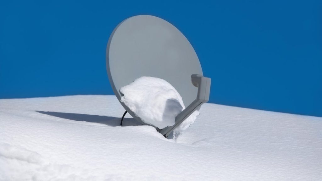 A satellite dish sitting on top of snow covered ground.