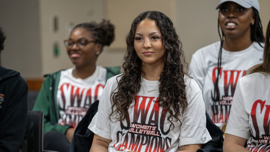 Two women wearing swag shirts and smiling for the camera.