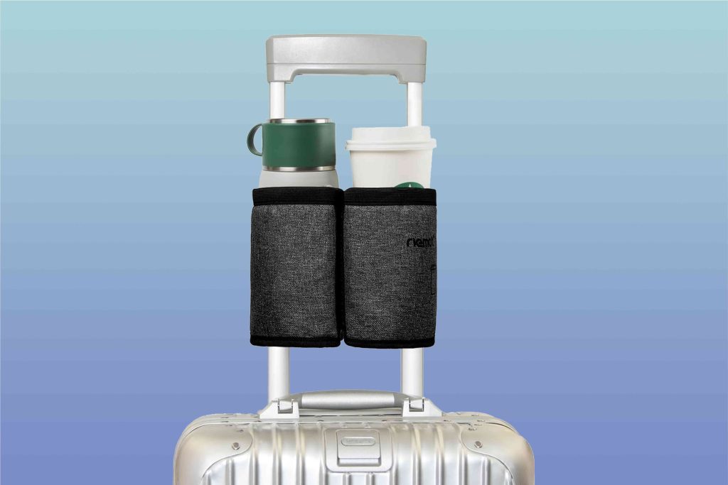 A suitcase with two bags and a cup on it