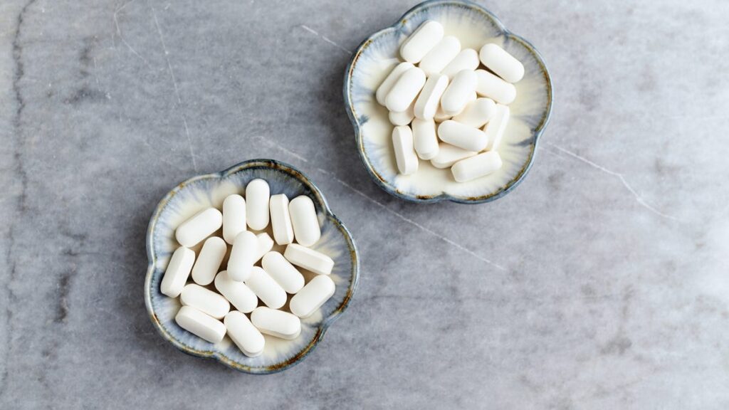 Two bowls of white pills on a table.