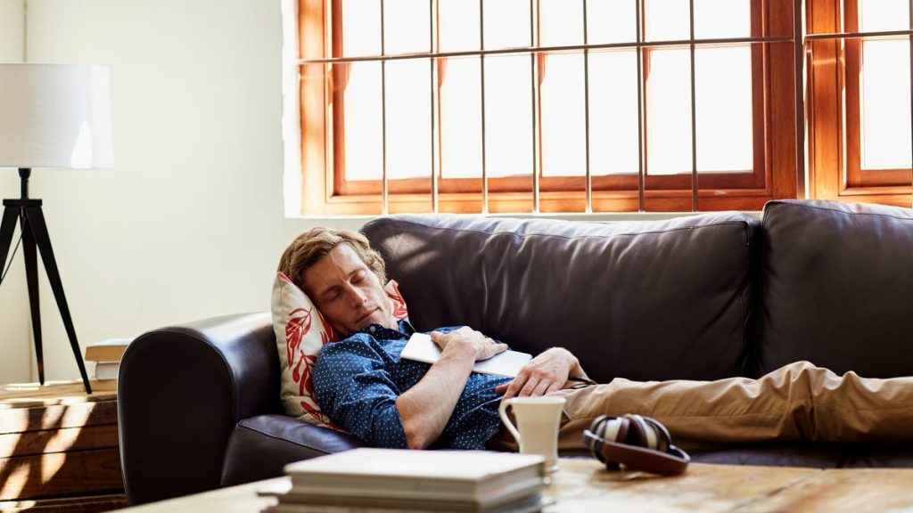 A man laying on the couch with his head resting on a pillow.