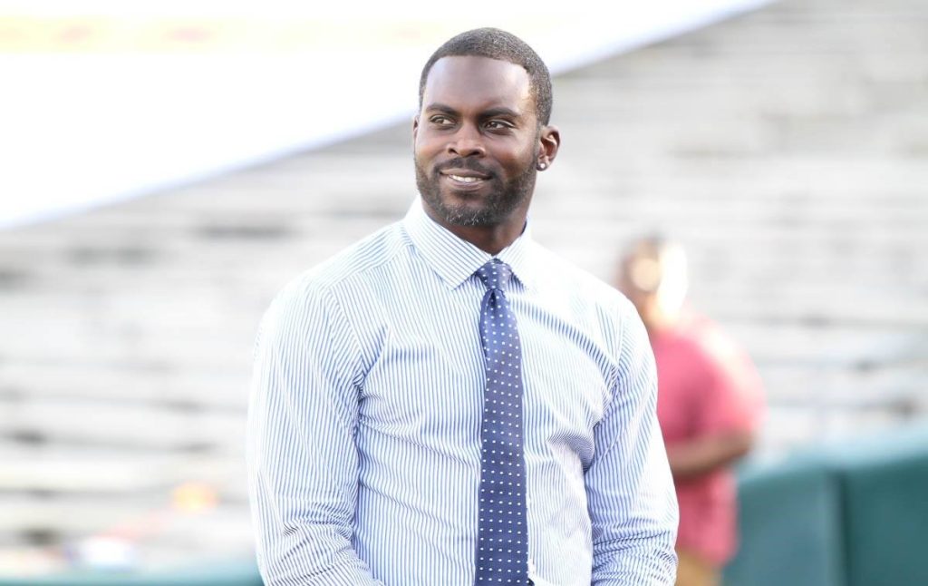 A man in a blue shirt and tie standing outside.