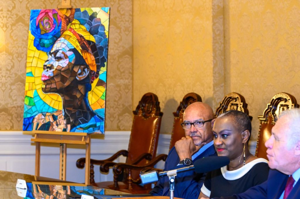 Two men sitting in front of a painting.