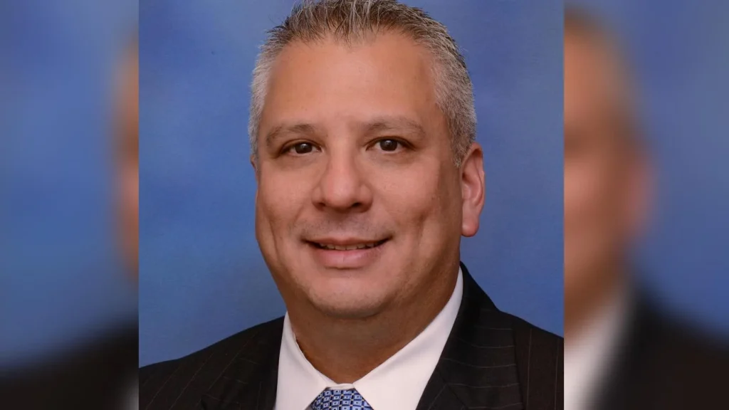 A man in suit and tie smiling for the camera.