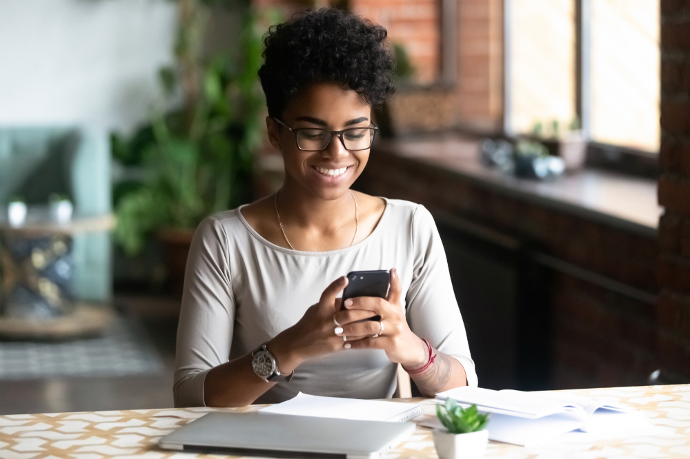 A woman sitting at a table looking at her phone.