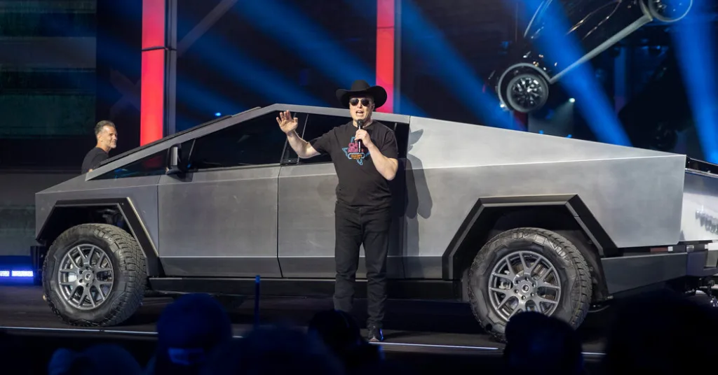 A man in black shirt and hat standing next to a truck.