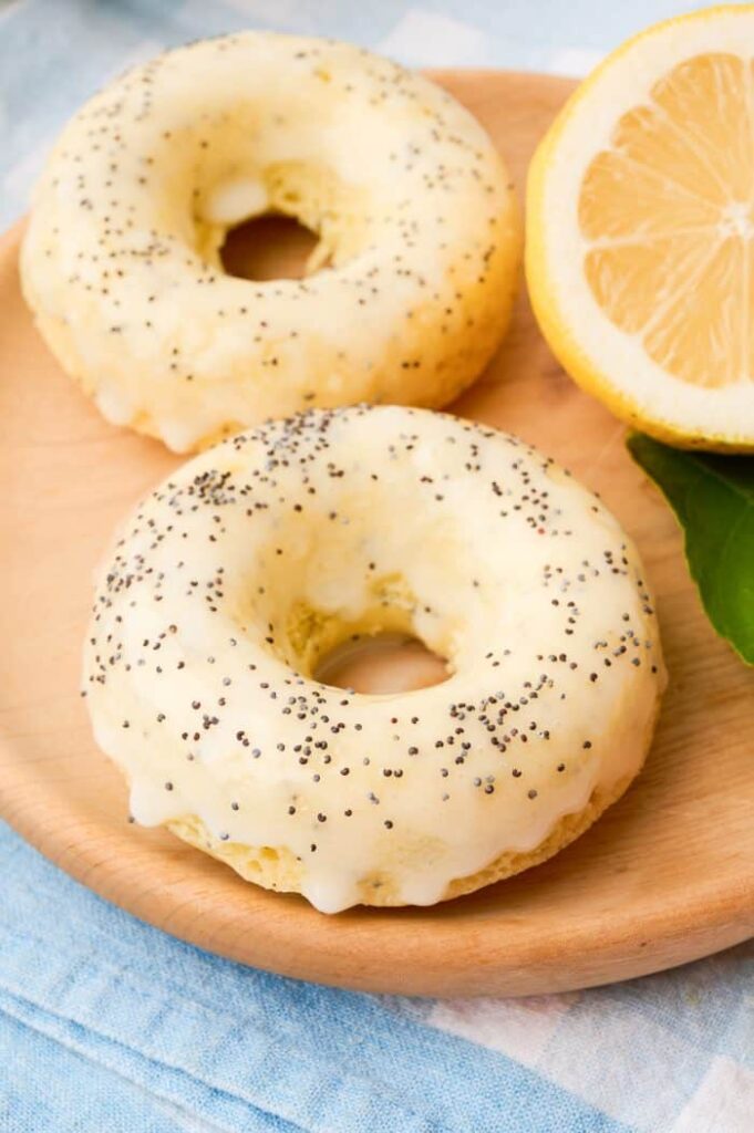 Two donuts on a plate with lemon and poppy seeds.