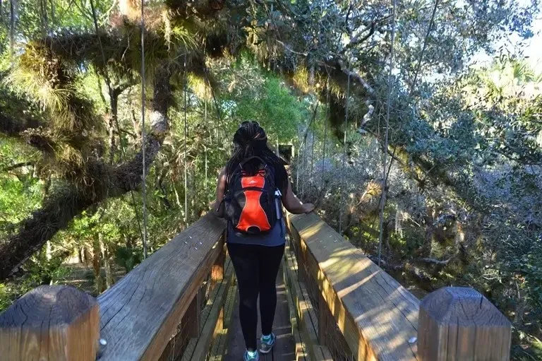 A woman walking on a bridge over water.