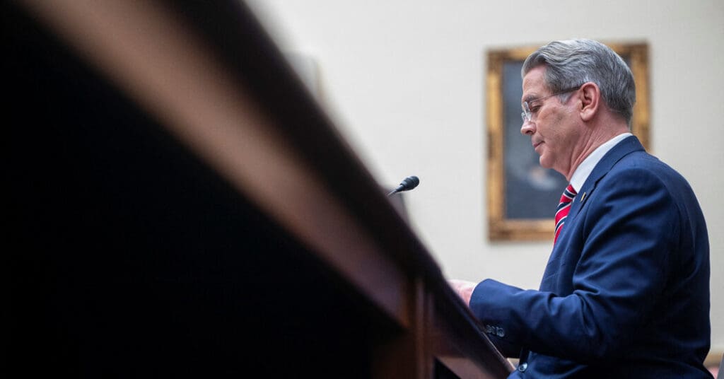 Man speaking at podium in formal setting.