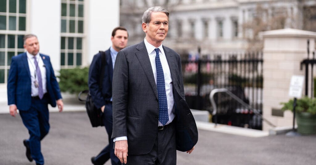 Man in suit walking with others outdoors.