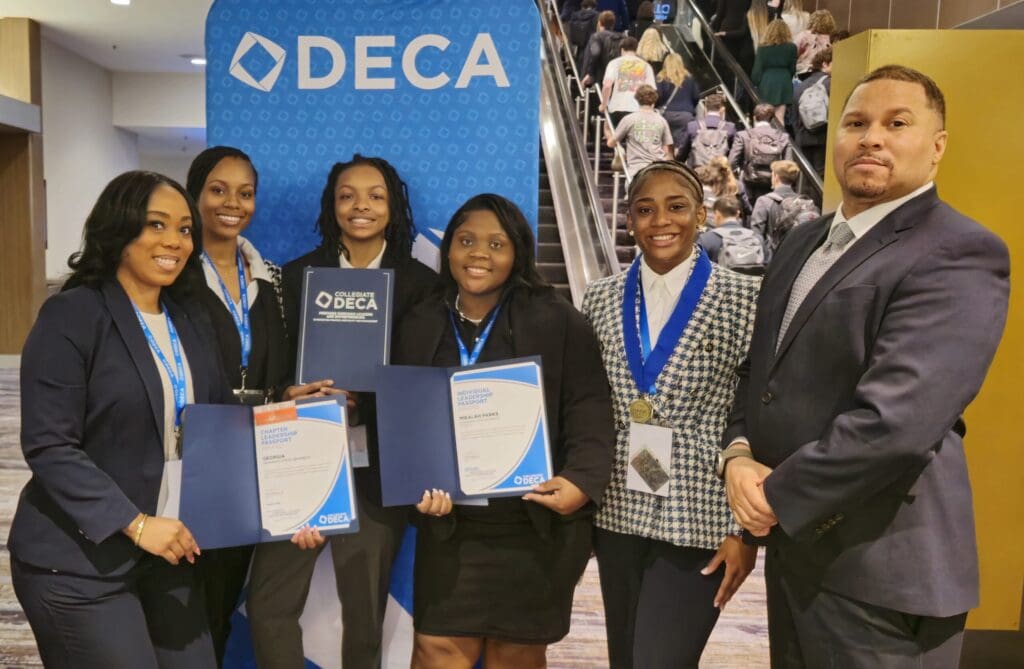 Group posing with DECA awards and certificates.