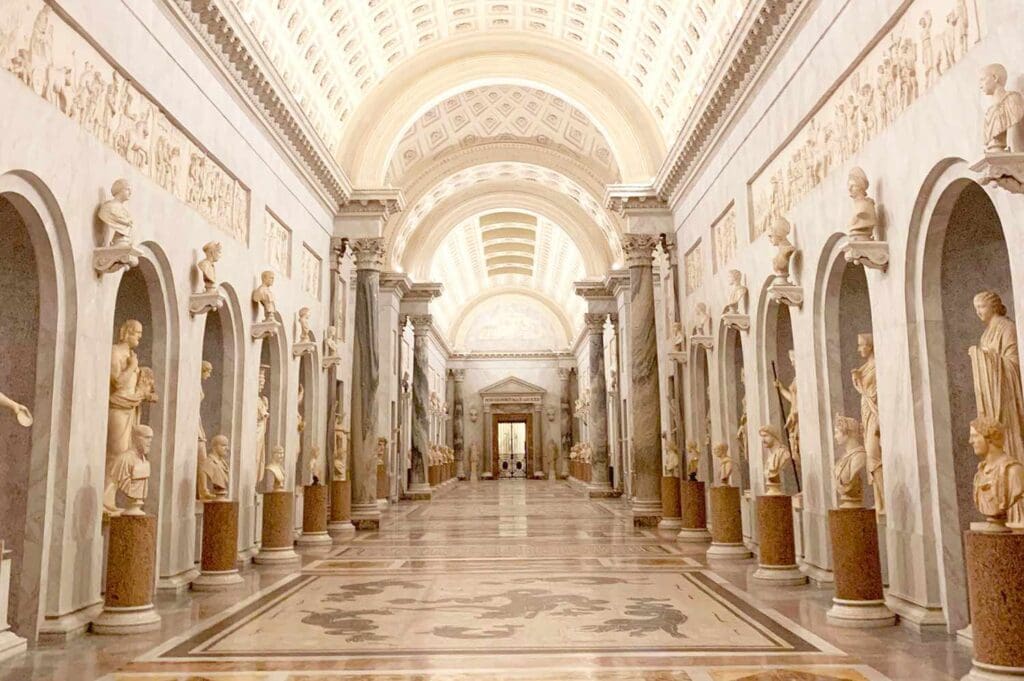 A grand corridor in the Vatican Museums, adorned with ornate arches and classical statues