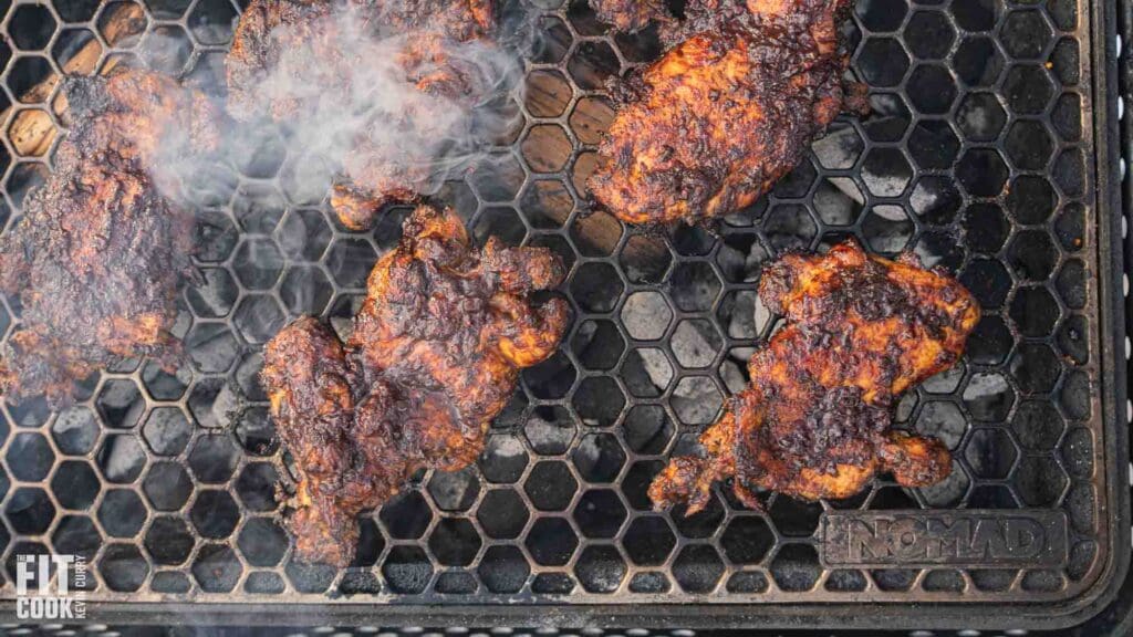 Grilled chicken thighs on a smoky grill.