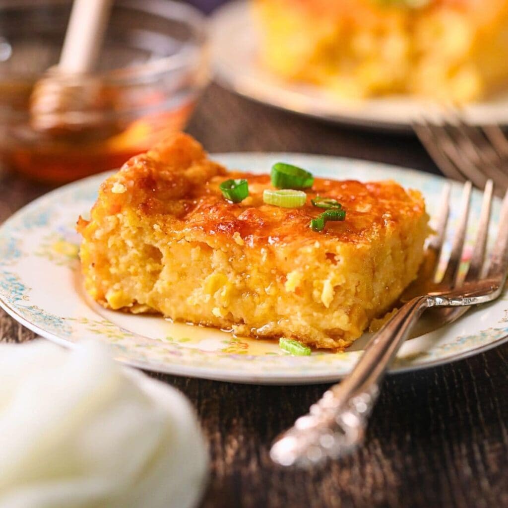 Photo of creamy cheesy corn casserole baked with cheddar and chives.