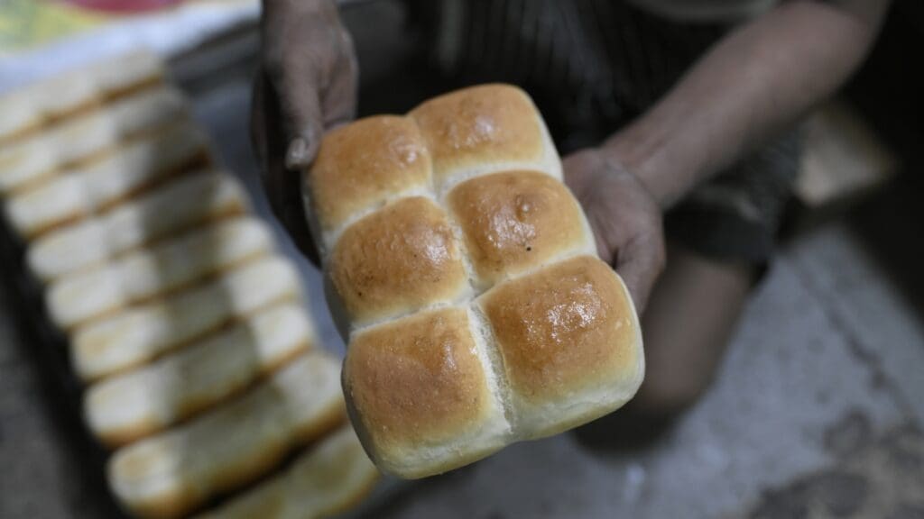 Person holding freshly baked bread rolls.