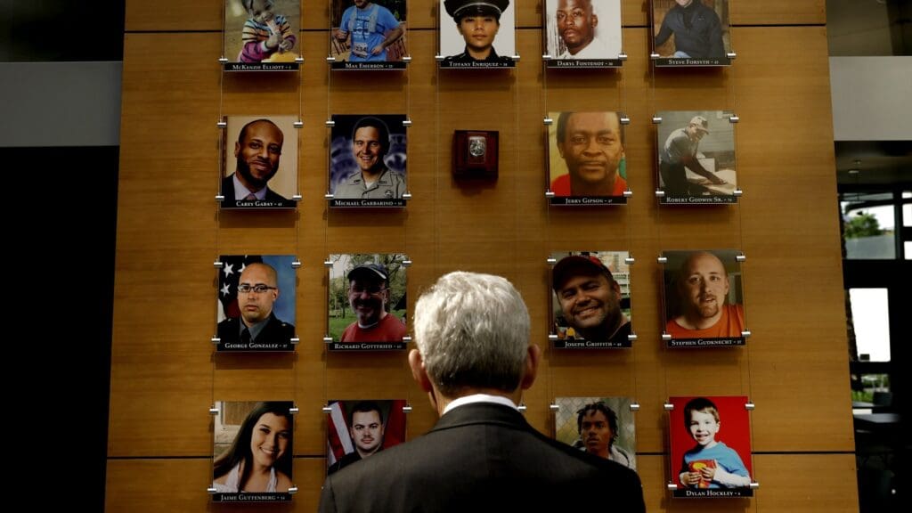 Man viewing a wall of portrait photos.