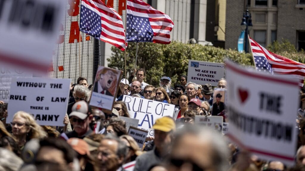 Protesters holding signs and American flags gathered.