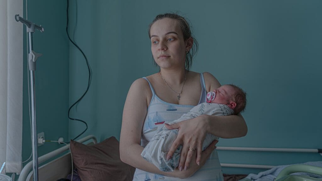 Woman holding newborn baby in hospital room.