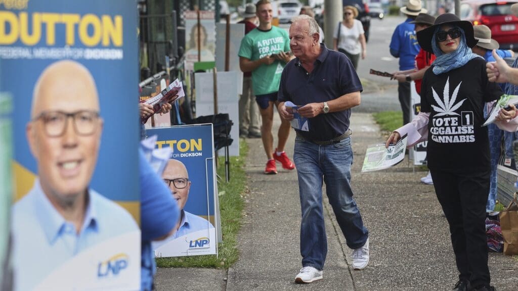People distributing flyers near election posters.